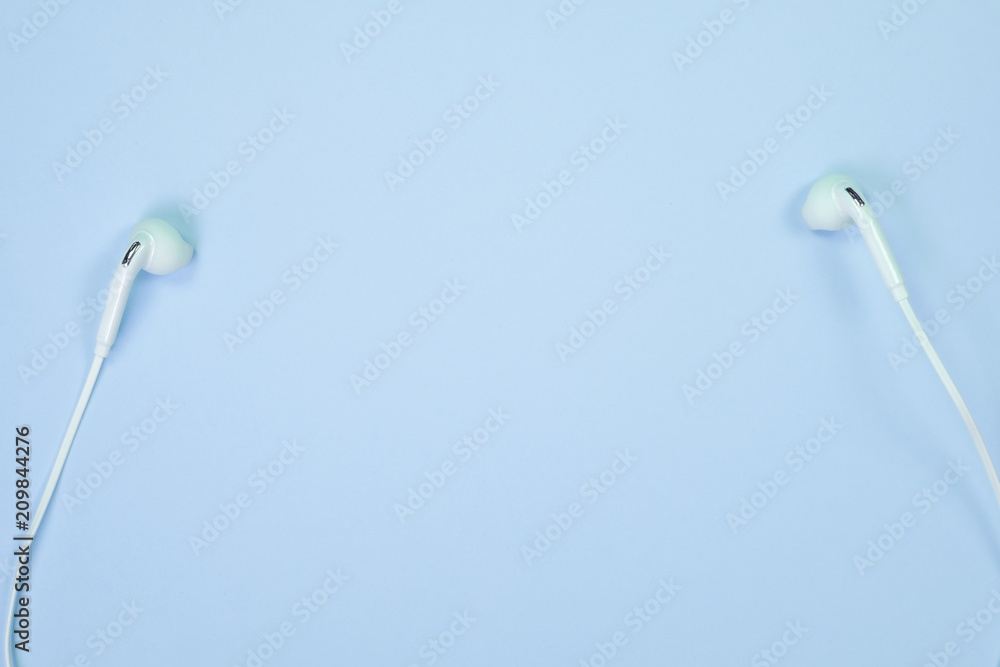 White Earphones or ear buds small talk on sweet blue colour pastel paper, top view, texture and background. music listening concept. White Earphones or ear buds small talk on sweet blue colour pastel paper, top view, texture and background. music listening concept.