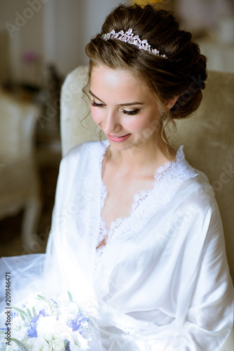 Beauty bride in dressing gown with bouquet indoors