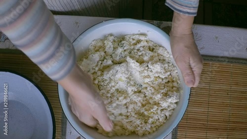 woman hand mix white cottage cheese with onions and boiled and mashed potatoes to fill traditional Polish dumplings , pierogi