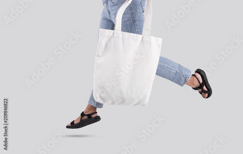 Dziewczyna trzyma torby płótno tkaniny dla makieta pusty szablon na białym tle na szarym tle.