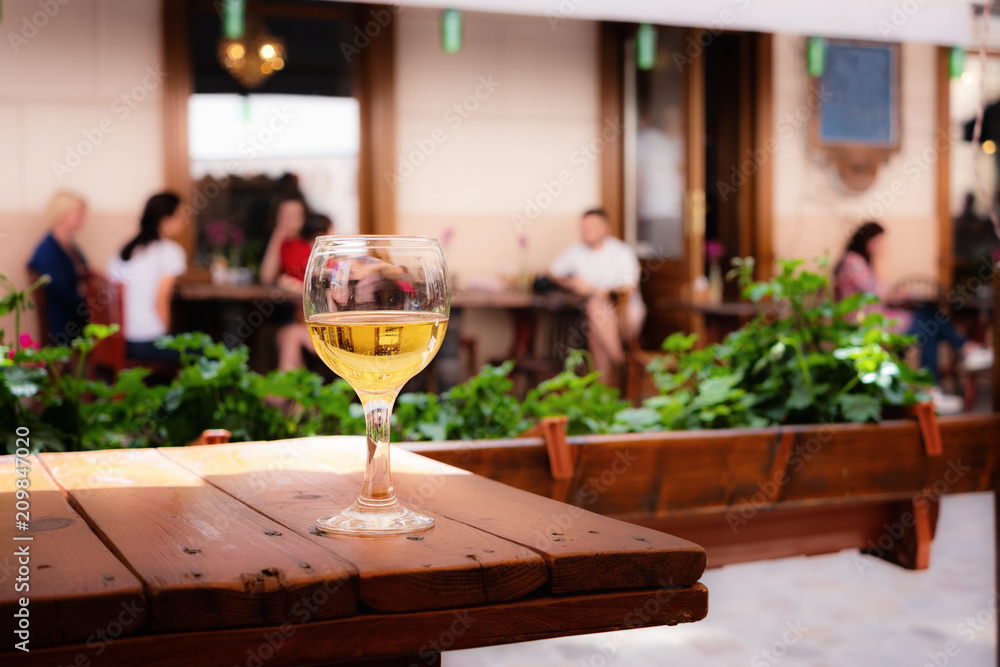 The glass of white wine standing on a table of street cafe