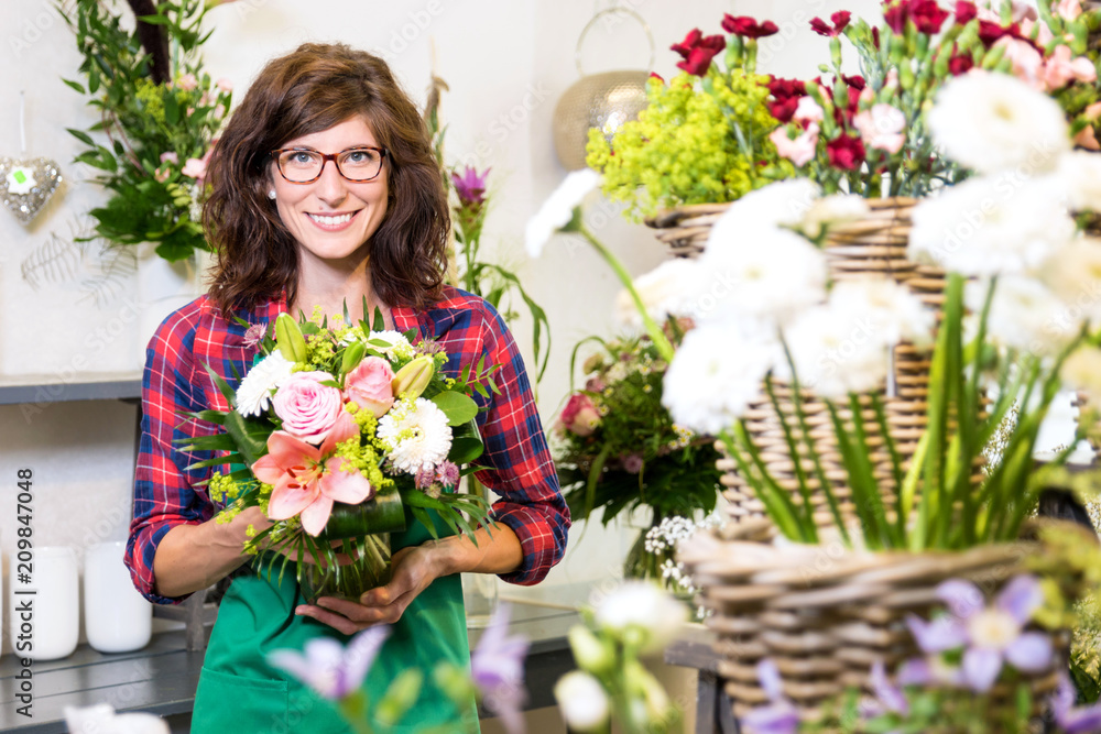 Freundlich lächelnde Floristin mit frisch gebundenem Blumenstrauss