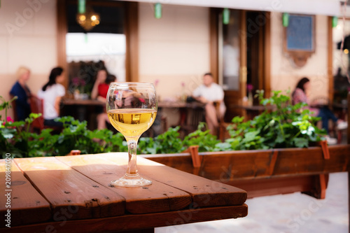 The glass of white wine standing on a table of street cafe