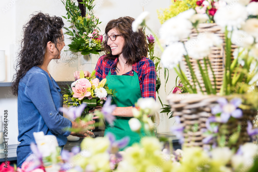 Freundlich lächelnde Floristin verkauft einer Kundin einen