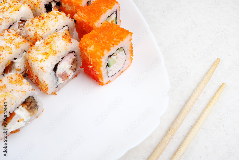 Sushi set on a white plate. Several varieties of sushi and chopsticks. Japanese traditional food. Sushi set on a white plate. Several varieties of sushi and chopsticks. Japanese traditional food.