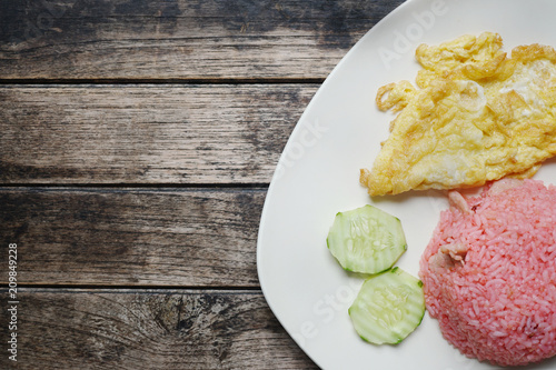 close up of pink rice with omelette on wood table