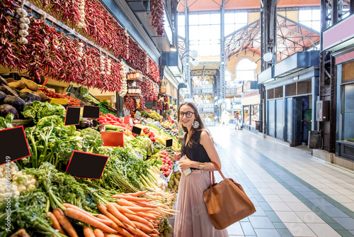 Young woman choosing goods standing at the counter with a bunch of different fresh food in theGreat Market hall in Budapest