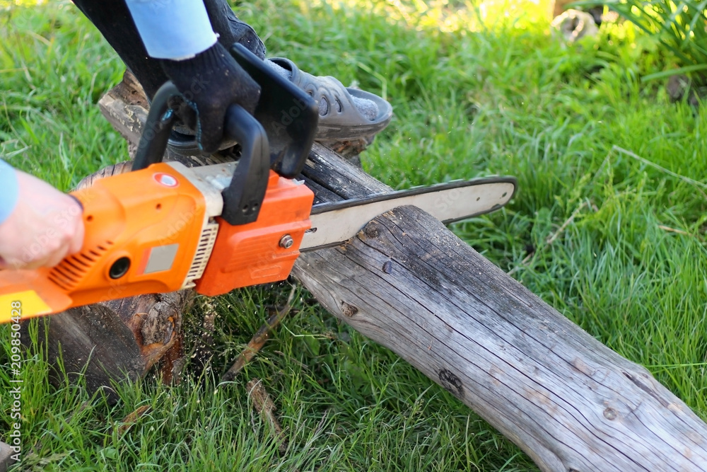 a man with an electric chainsaw sawing a log