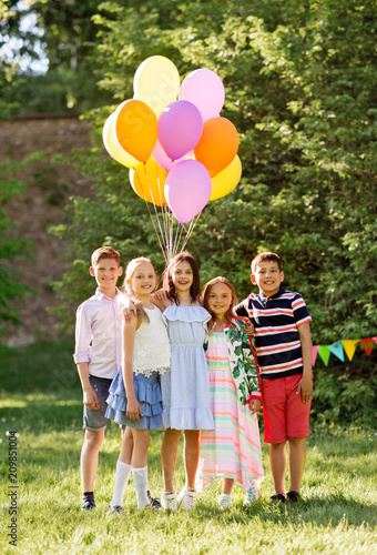 holidays  childhood and celebration concept - happy kids with balloons on birthday party at summer park