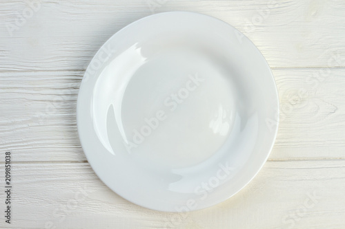 Top view of white empty plate. Ceramic plate on white wooden background.
