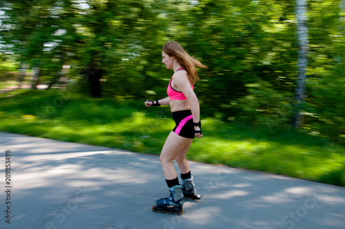 Roller skating woman in park rollerblading on inline skates.