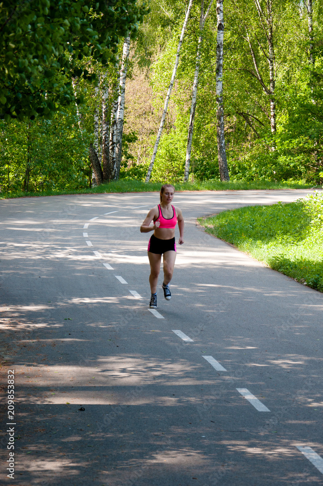 Beautiful smiling woman running in the park in the morning. Fitness girl running in the park. Running woman. Female Runner Jogging during Outdoor Workout in a Park. Beautiful fit Girl. Beautiful smiling woman running in the park in the morning. Fitness girl running in the park. Running woman. Female Runner Jogging during Outdoor Workout in a Park. Beautiful fit Girl.