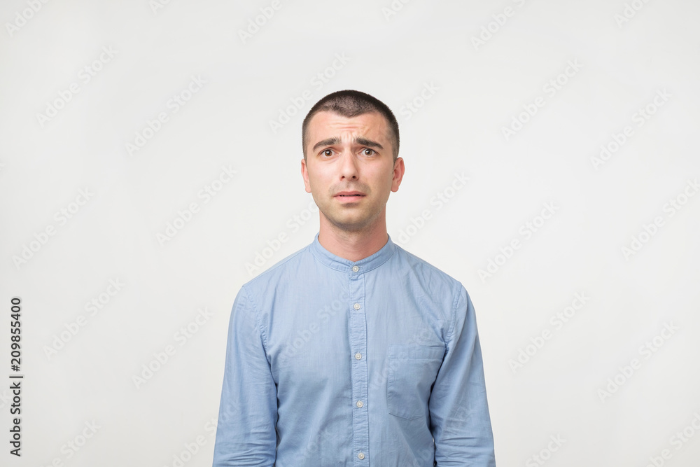 Close up of a doubtful young man in blue shirt. He is not sure what to do. Close up of a doubtful young man in blue shirt. He is not sure what to do.