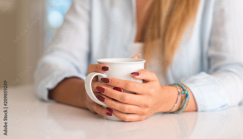 Woman holding a cup of coffee at home Woman holding a cup of coffee at home