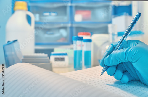 Biological or biochemical lab out of focus  closeup on gloved hand writing a note
