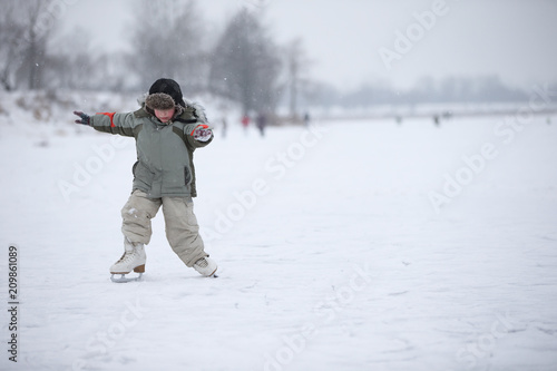 The child learns to skate on the lake. A boy ice skating on an ice river on a snowy winter day
