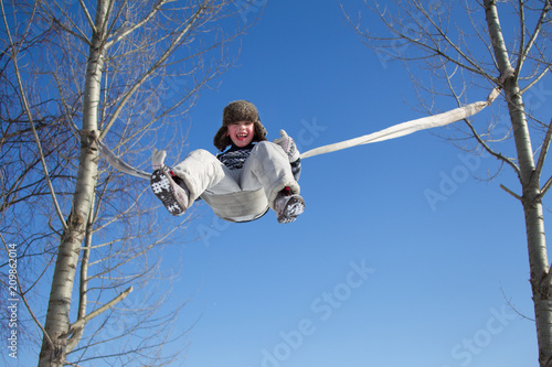 Wallpaper Mural A little boy is riding a rope swing on a winter day high Torontodigital.ca