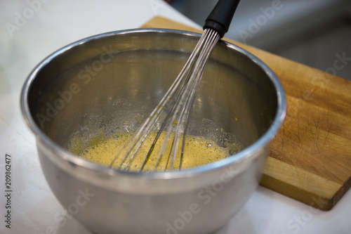 Bowl with whisk and beaten eggs