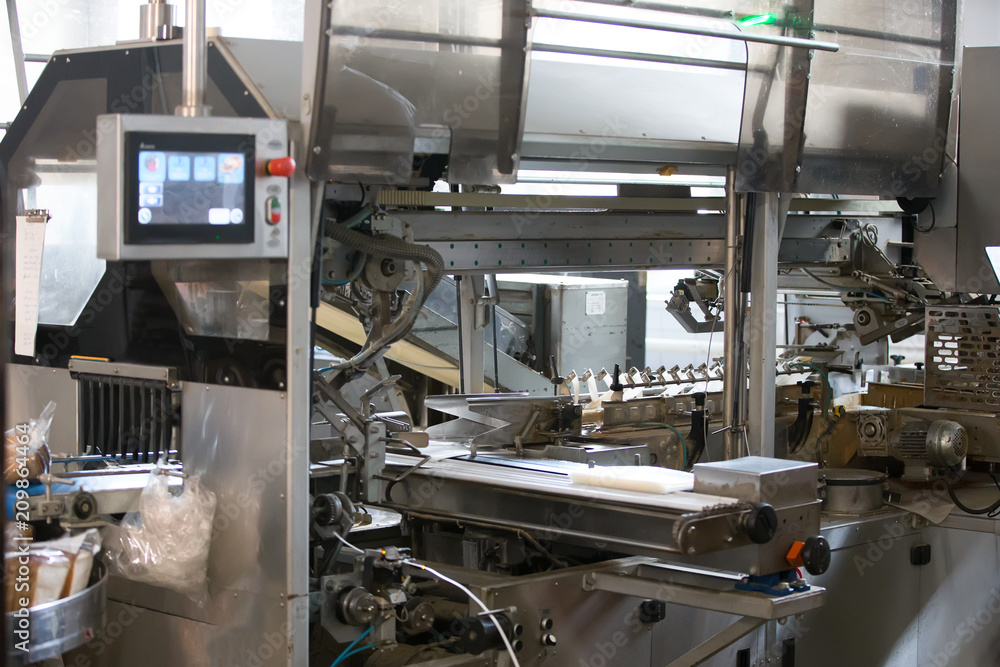 Industrial line for packaging of bakery products. Packing of bread at the factory.The machine for cutting and packing in a factory for the production of bread. Industrial line for packaging of bakery products. Packing of bread at the factory.The machine for cutting and packing in a factory for the production of bread.