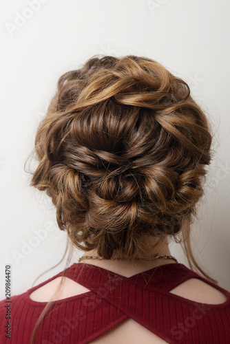 Wedding hairstyle bun on the head of brown-haired women on a gray background close-up rear vie