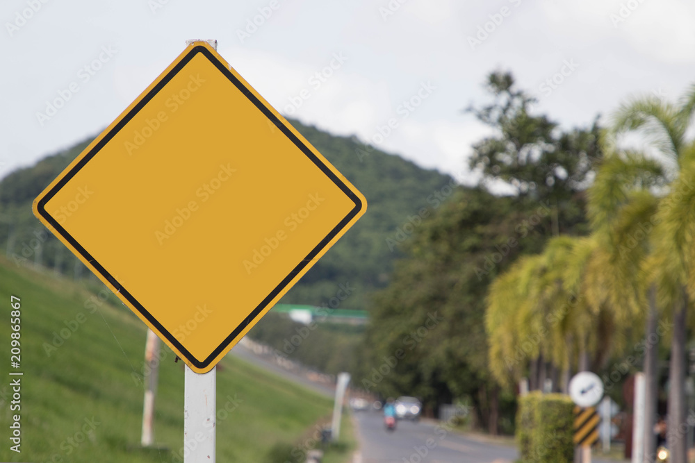 Empty yellow traffic sign on blur traffic road with colorful light abstract background.