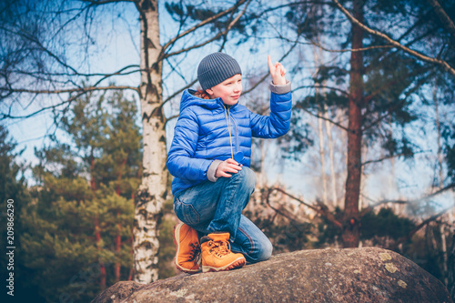 Young red-haired adventurer determines the direction of the wind with the help of a finger