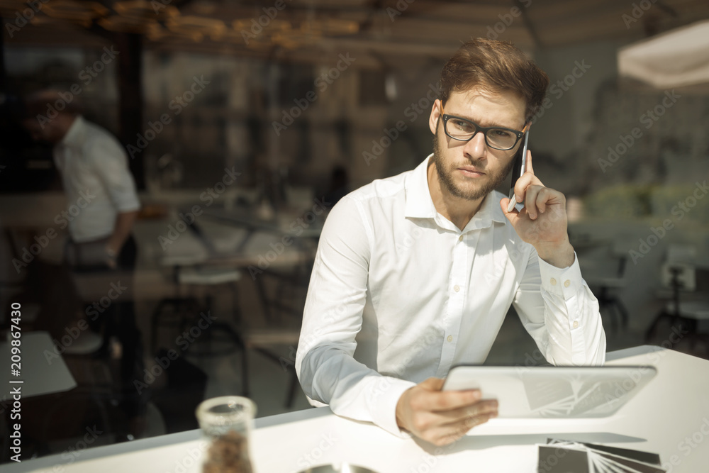 Handsome businessman using phone and wearing glasses
