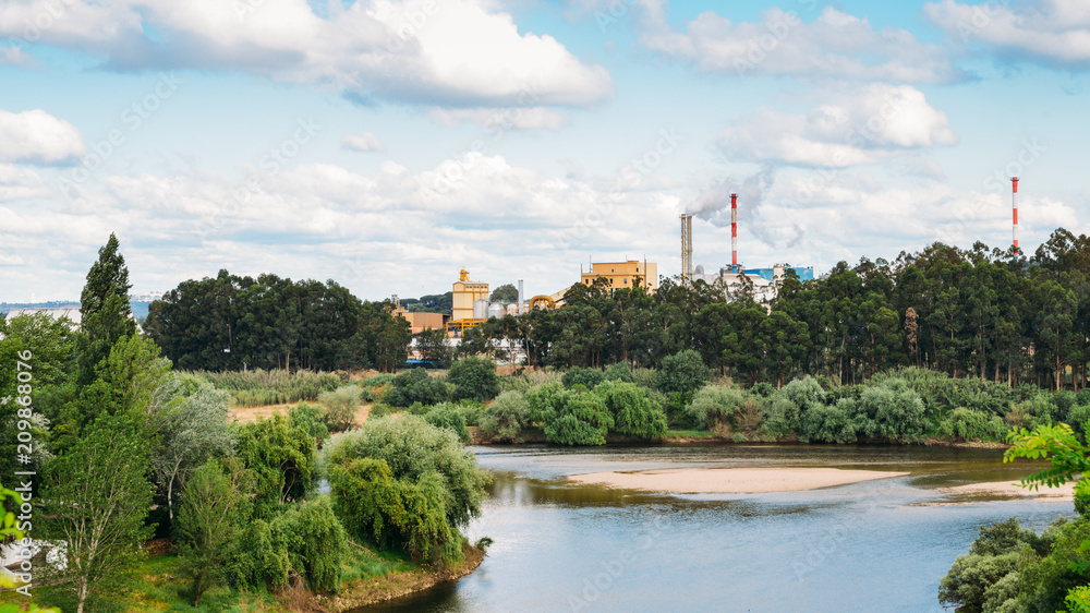 Factory next to river emiting plumes of smoke. Factory next to river emiting plumes of smoke.