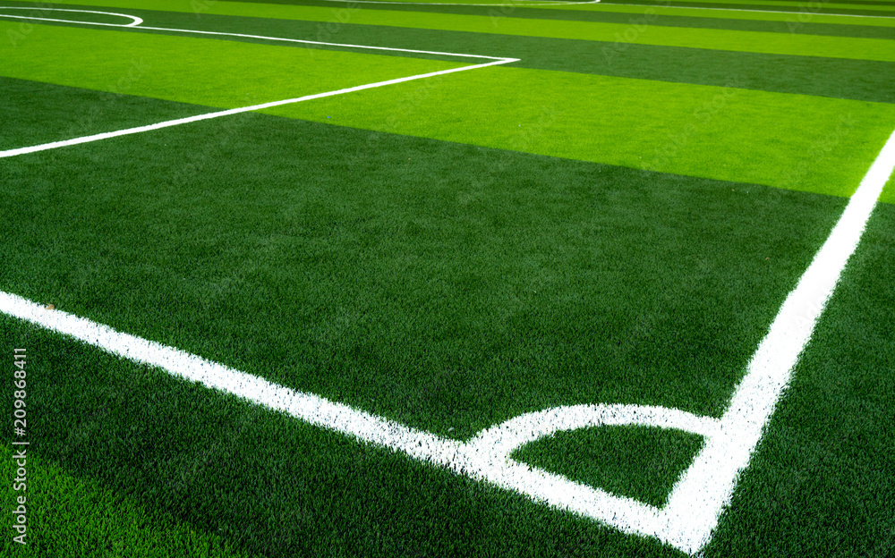 Green grass soccer field. Empty artificial turf football field with white line. View from the corner of soccer field. Sport background