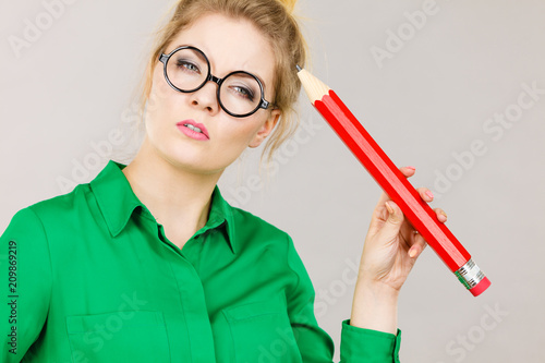 Woman confused thinking, big pencil in hand