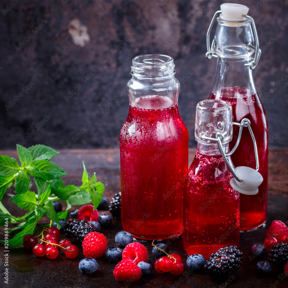 Drink Summer from Mix Berries Decorated with Green Mint. Compote in Glass Bottles. Old dark Background. Superfoods and healthy lifestyle or detox diet food concept. Drink Summer from Mix Berries Decorated with Green Mint. Compote in Glass Bottles. Old dark Background. Superfoods and healthy lifestyle or detox diet food concept.