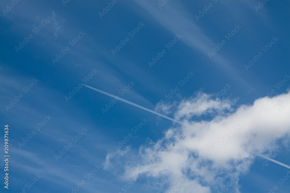Aircraft trail of jet against the wide blue sky width clouds Aircraft trail of jet against the wide blue sky width clouds