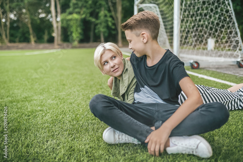 happy mother and son smiling each other while resting together on green lawn © LIGHTFIELD STUDIOS