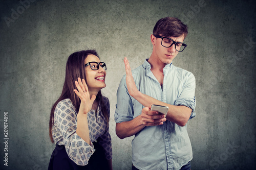 Annoying woman trying to distract young handsome man texting on smartphone photo