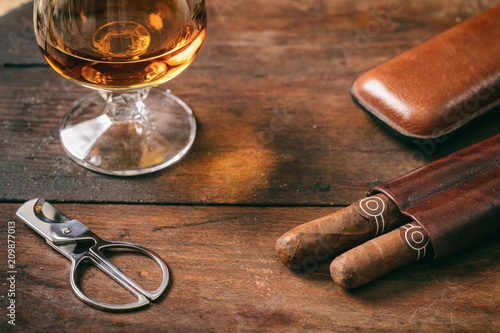 Canvas Print Cuban cigars closeup on wooden desk, blur glass of brandy