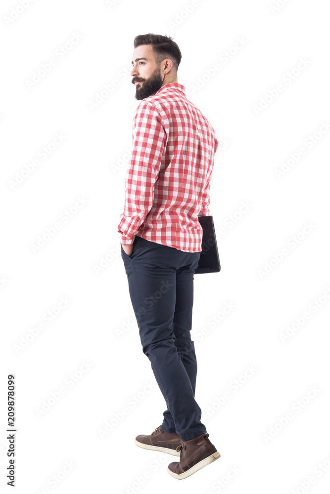 Back view of confident handsome young bearded man holding laptop and walking away. Full body isolated on white background. Back view of confident handsome young bearded man holding laptop and walking away. Full body isolated on white background.
