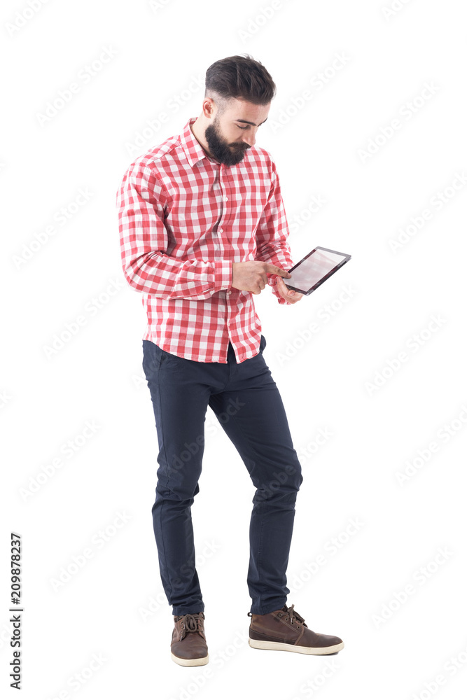 Young bearded stylish business man using tablet touch screen with finger. Full length isolated on white background. Young bearded stylish business man using tablet touch screen with finger. Full length isolated on white background.