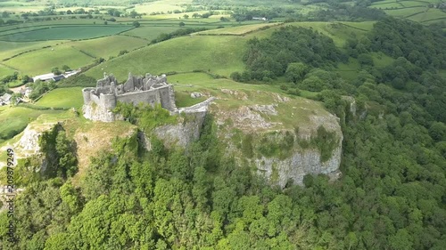 Aerial drone view of the ruins of a medieval castle located on a hilltop overlooking farmland (Carreg Cennen, Wales) photo