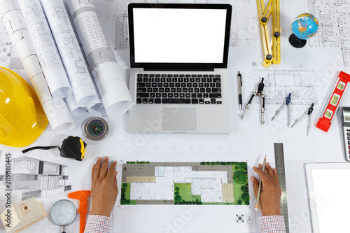 Architect or engineer holding blueprint and engineering tools on working table. Architect or engineer working on blueprint in office.