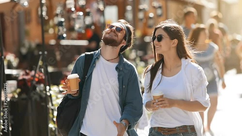 Positive young couple chatting happily as strolling in old european city, having pleasant talk while walking on amazing summer afternoon