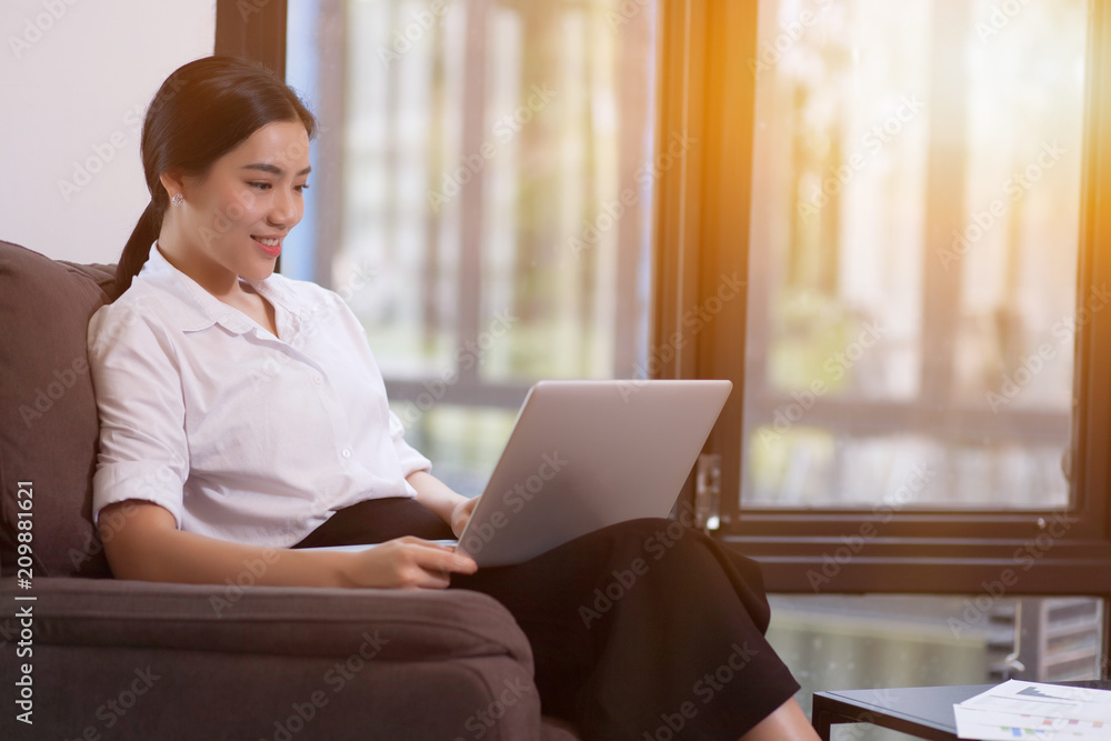 Young woman using laptop at the office near to big window. Young woman using laptop at the office near to big window.