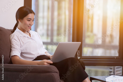 Young woman using laptop at the office near to big window.