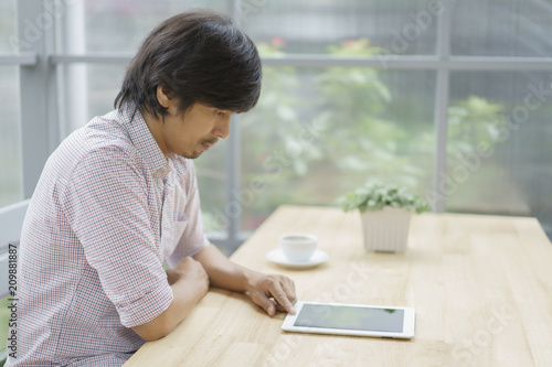 Asian men using digital tablet in the cafe. Free Download Asian men using digital tablet in the cafe. - GFXLoad