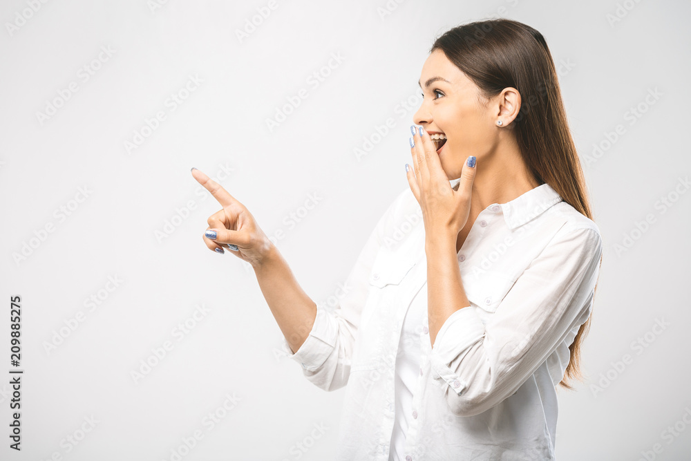 Young beautiful smiling woman presenting your product, isolated over white background. Place for text. Surprised woman looking sideways in excitement. Isolated over white background Young beautiful smiling woman presenting your product, isolated over white background. Place for text. Surprised woman looking sideways in excitement. Isolated over white background