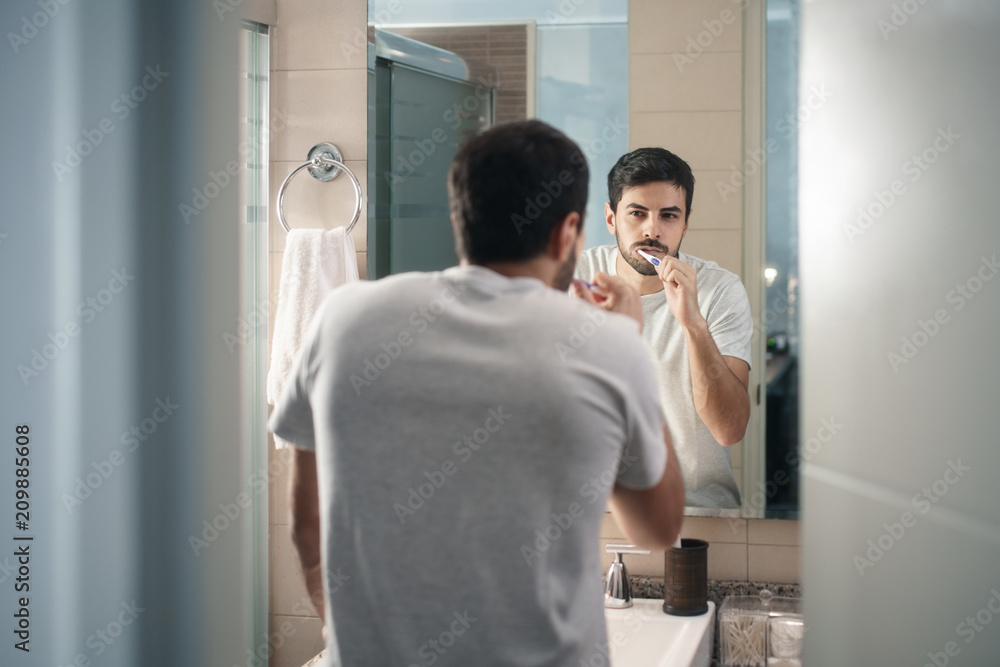 Fototapeta premium Hispanic Man Brushing Teeth In Bathroom At Morning