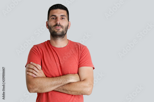 Portrait of young man looking at camera, studio shot on the grey background