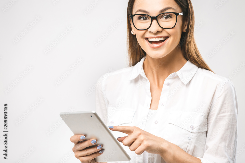 Wow! It's amazing. Portrait with copy space empty place of pretty charming confident trendy woman in classic shirt having tablet in hands and looking at camera isolated on white background.