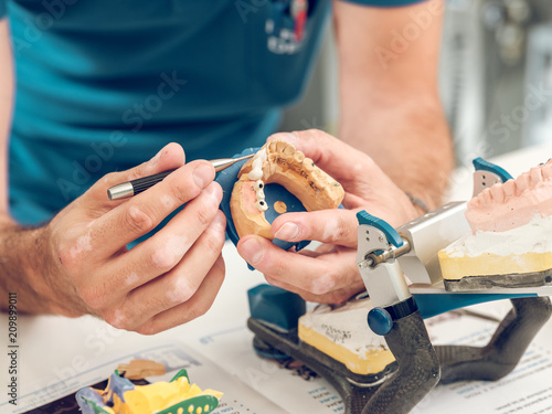 Hands of technician making denture photo