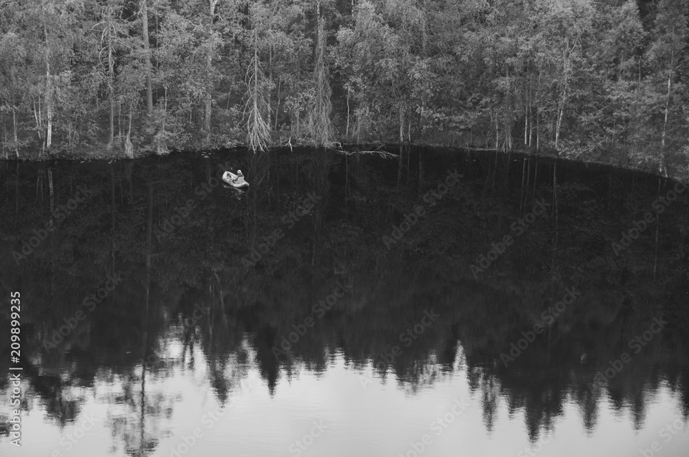 Black and white image of a fisherman on a forest lake