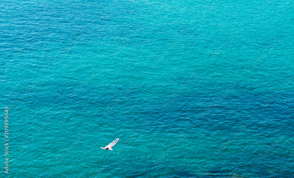 man relaxes in the crystalline water of the sea